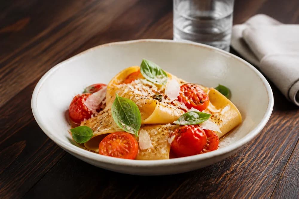 Illustrative bowl of fresh tomato and basil pasta on a restaurant table, with no people